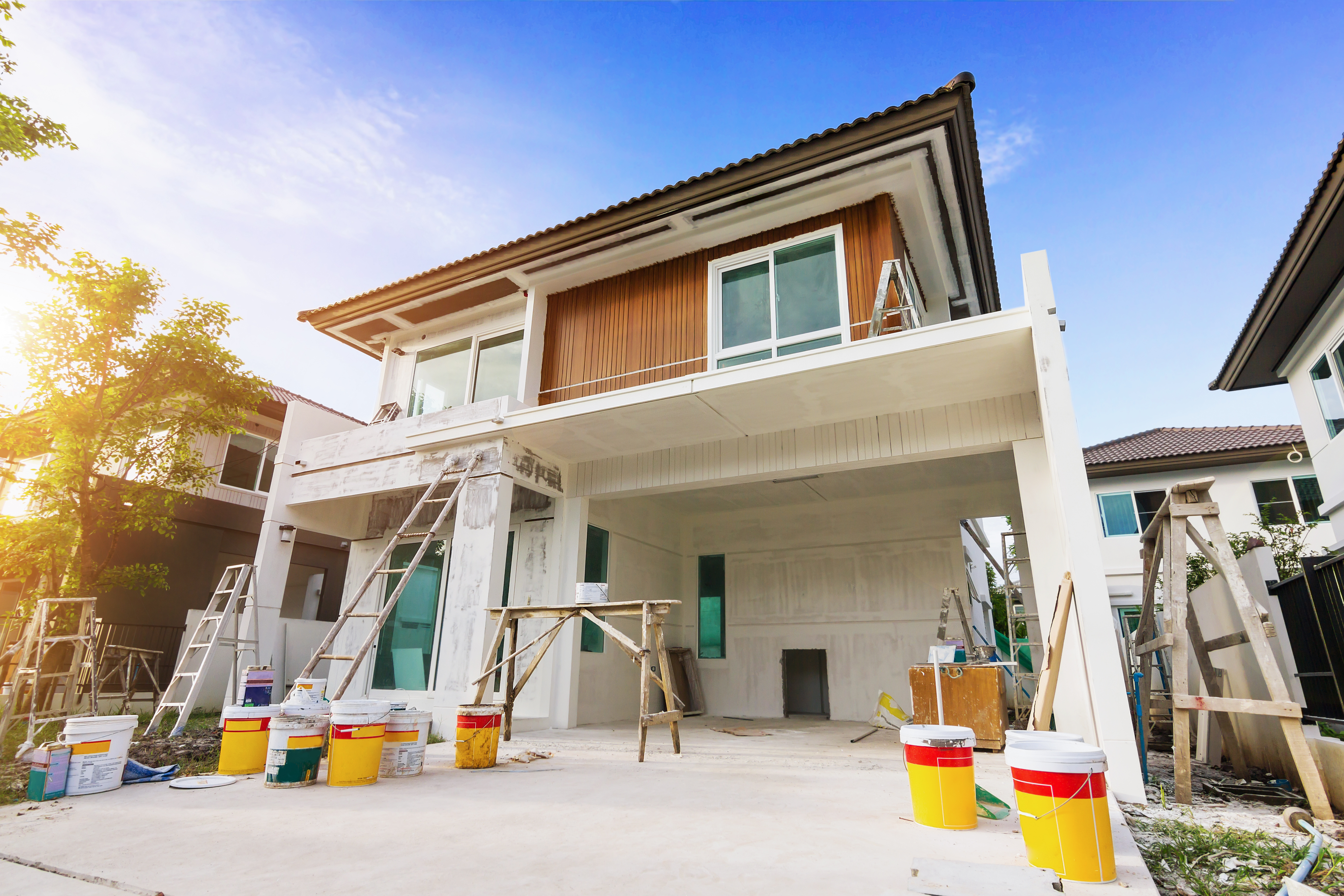 Modern two-story house under construction with white exterior and wooden upper level details